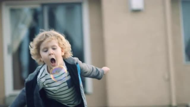 4 year old boy chases a bubble and pops it with his mouth slow motion