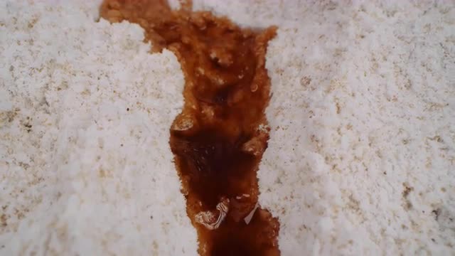 Macro dolly across flour mixture as vanilla extract pours and soaks in