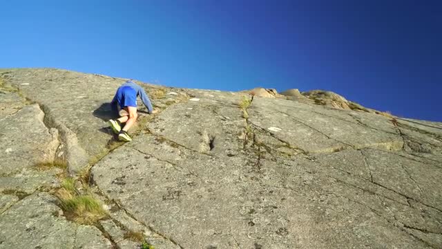 boy climbing steep mountain in Bohuslän