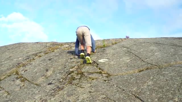 young boy climbing to top of steep mountain