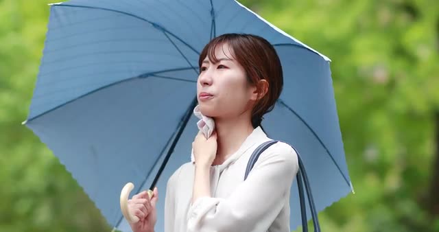 Young Japanese woman repairing from the Summer sun with umbrella downtown Tokyo