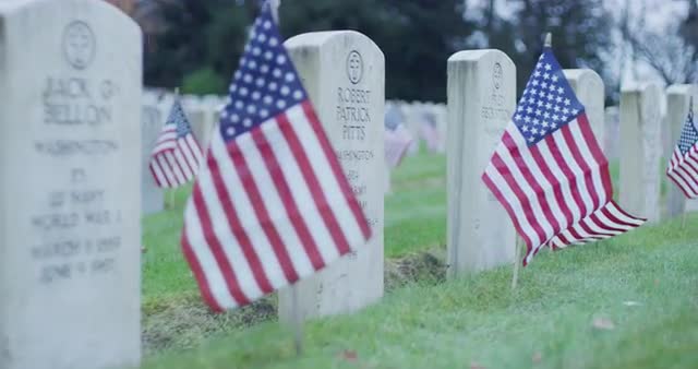 Gimbal shot of veteran gravestones and flags in cemetery