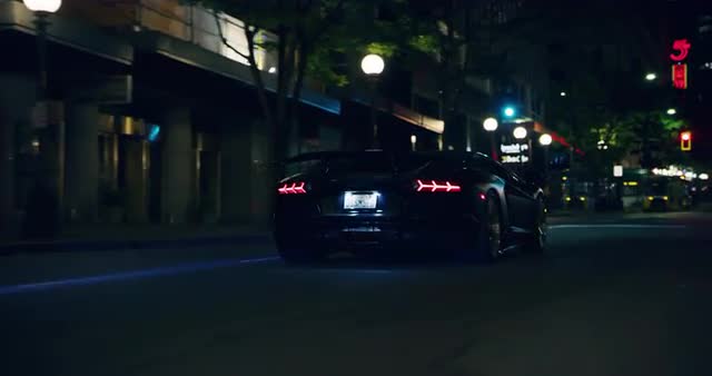 Medium shot of black Lamborghini driving through city streets