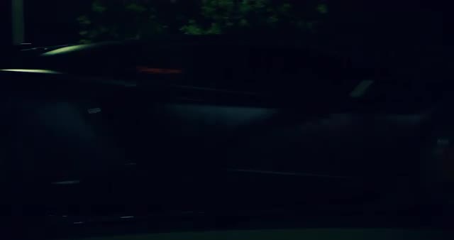 Medium shot of black Lamborghini driving through city streets