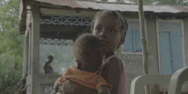 A Haitian Toddler Cradles A Baby