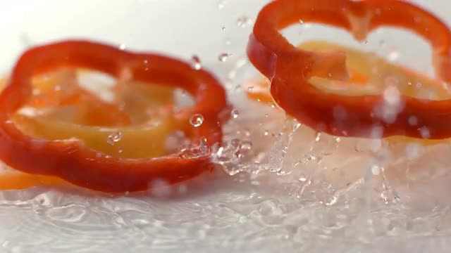 Bell pepper slices splashing in water, slow motion