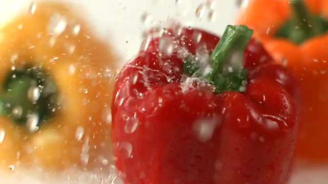 Water splashing on bell peppers, slow motion