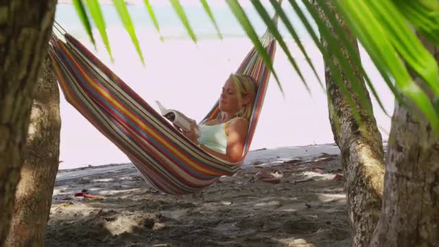  Woman sitting in hammock reading book, Costa Rica