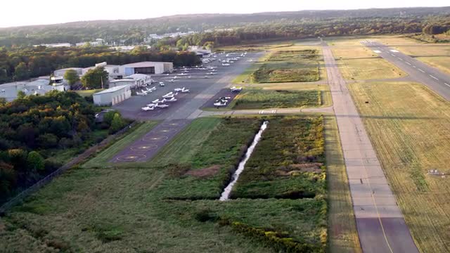 WIDE AERIAL POV over small airport toward parked airplanes