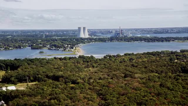 LONG AERIAL POV toward cooling towers of Brayton Power Plant on waterfront of Mount Hope Bay in Some