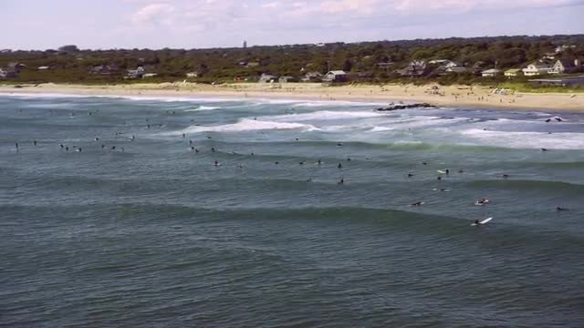 WIDE AERIAL SIDE POV  PAN beach and ocean with swimmers and surfers