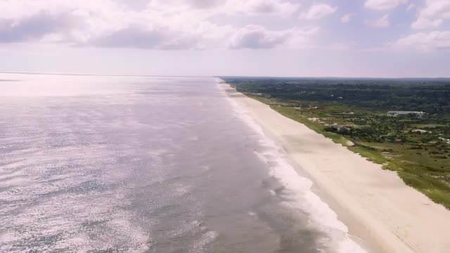 WIDE AERIAL POV along beach on Atlantic Ocean