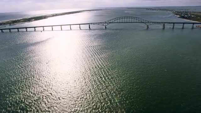 WIDE AERIAL POV toward and over Robert Moses Causeway over Fire Island Inlet between Long Island and