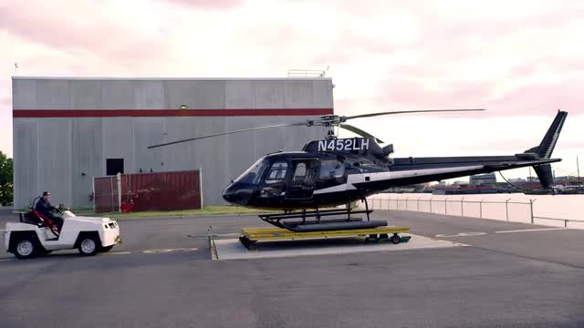 WIDE SHOT man backs cart away from helicopter parked at heliport in Kearney, New Jersey