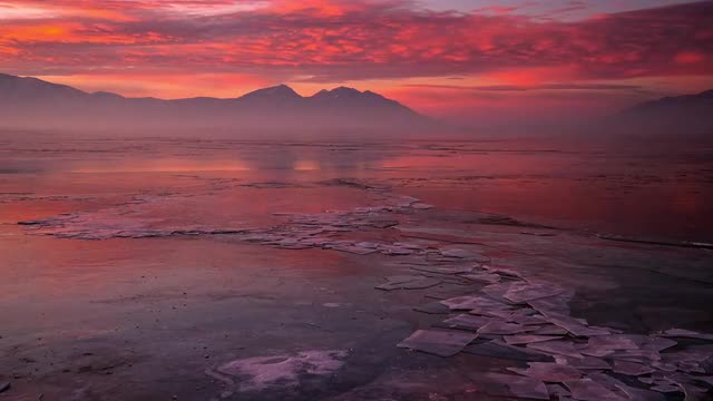 Timelapse over frozen lake during colorful sunrise with cracked ice