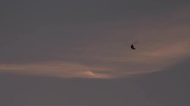 Helicopter Drifts Through Sky with Searchlights