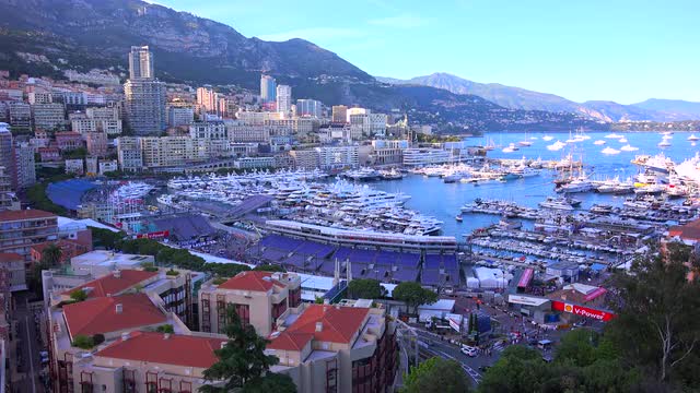 Wide angle establishing shot of Monaco includes the harbor and surrounding hills.