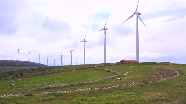 Wide shot of windmills generating electricity near traditional villages in Spain.