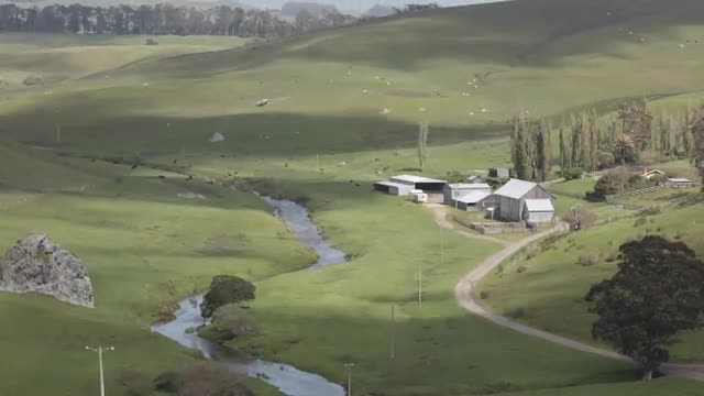 Hours of clouds shadows pass over a green pasture in a matter of seconds.