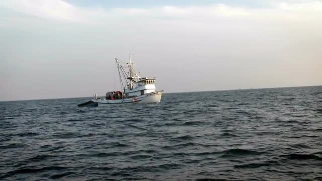 A boat with a dinghy sits on the water.