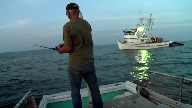 A man fishes from the back of a small boat.