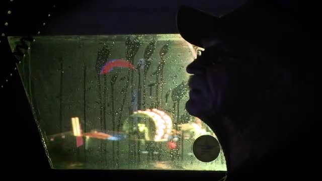 A man looks through a boat window as the rain falls.