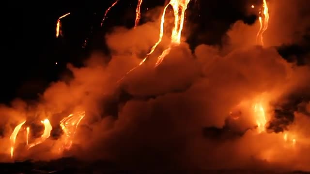Spectacular nighttime lava flow from a volcano into ocean.