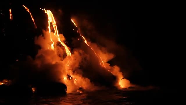 Spectacular nighttime lava flow from a volcano into ocean.
