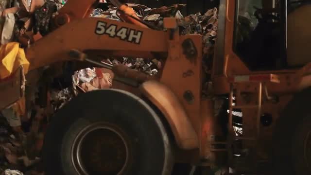 Skip loader shovels recycling at a factory.