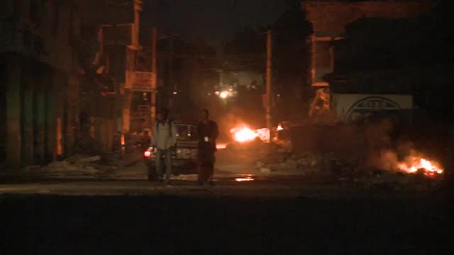 Open fires burn in a rough neighborhood in a third world country.