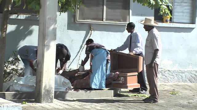 A victim of the Haiti earthquake is loaded into a coffin.