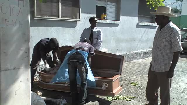 A victim of the Haiti earthquake is loaded into a coffin.