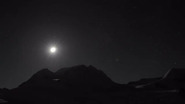 Moon setting behind mountain.