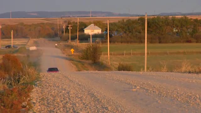 A pickup truck drives down a country road.