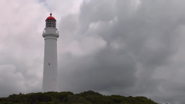 A lighthouse stands among an overcast sky.