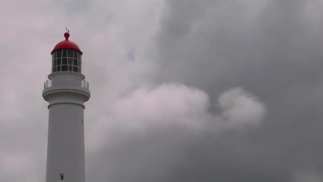 A lighthouse stands with an overcast sky in the background.