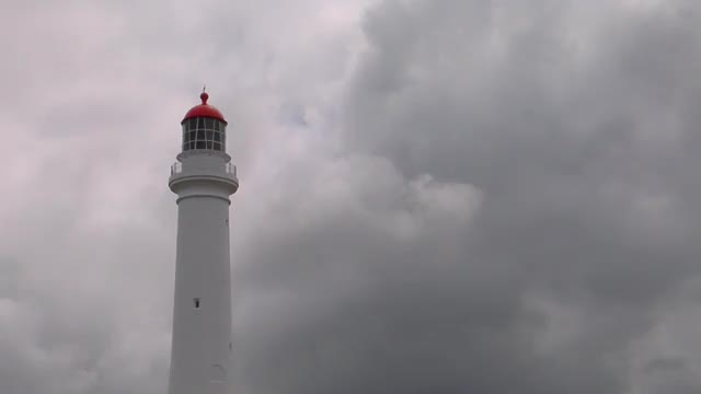 A lighthouse stands ready in the murk of an overcast day.