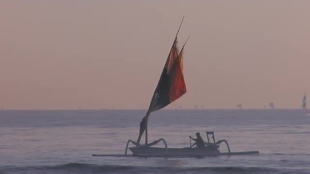 People row a fishing boat to into shore off the coast of Southeast Asia.