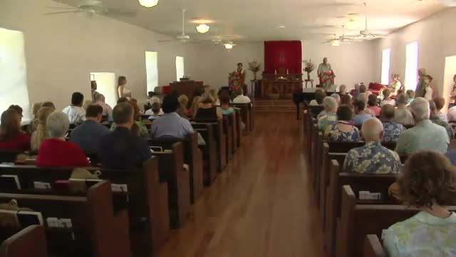 Pan across the interior of a small town church with many worshippers.