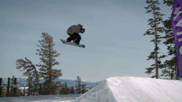 A snowboarder makes a jump off a large pile of snow.