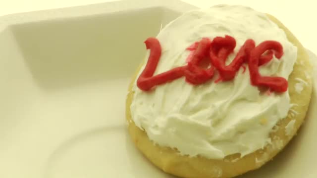 A cookie with the word "Love" spelled out in icing is featured in a bowl.