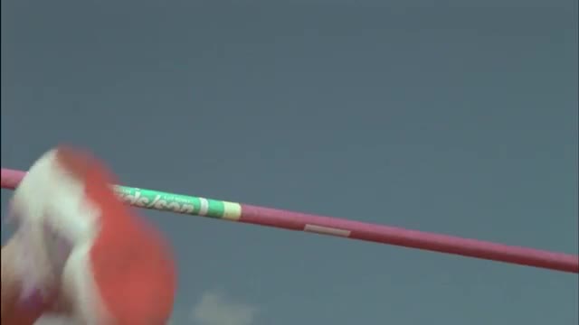 A young woman high jumps over a pole.