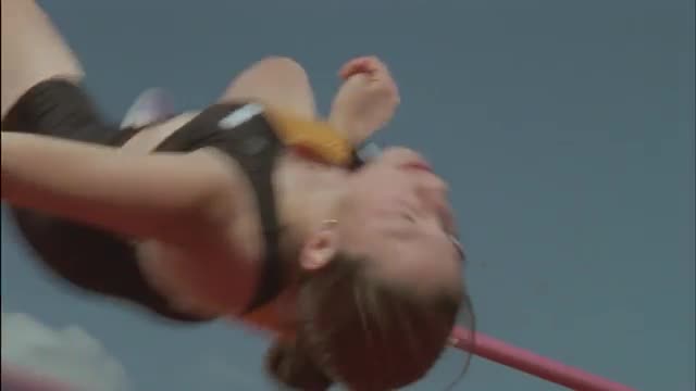A woman athlete performs a high jump.