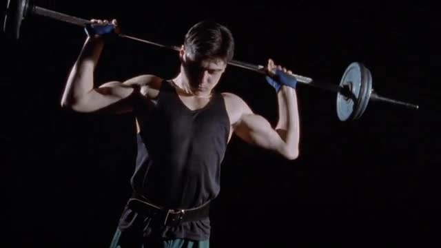 A young man lifting weights over his head.