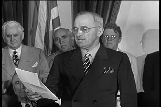 Harry Truman announces the surrender of the Japanese as reporters run to file the story.