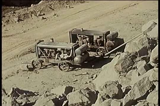 Construction of a broad highway and clearing rock in the early 1960's in California.