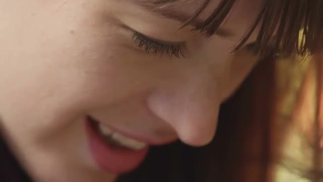 Close up of a smiling young woman who then looks up and smiles at the camera
