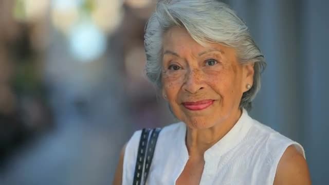 Medium shot of an old Spanish lady looking into the camera and smiling