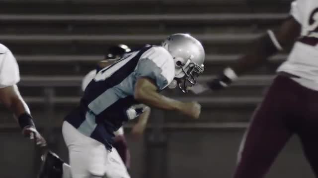 A football player runs with the ball while players trying to tackle him miss