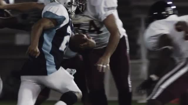 A football player runs with the ball while players trying to tackle him miss